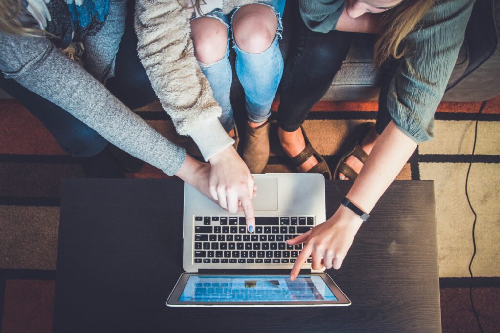A group of people is pointing at the laptop